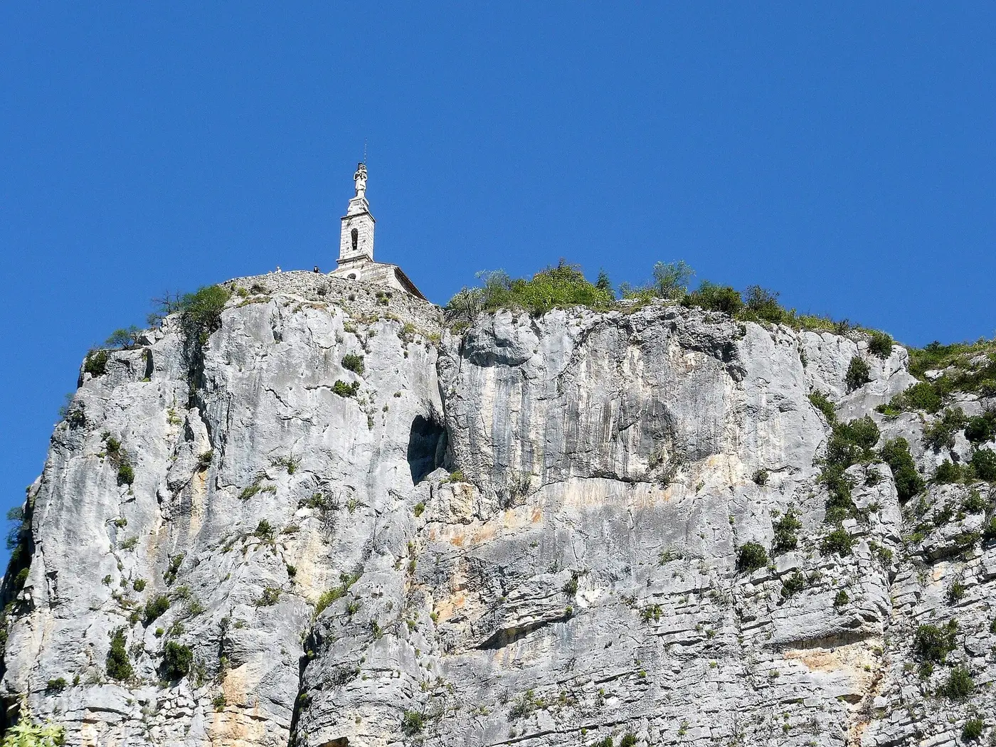 Le Roc de Castellane et la chapelle Notre-Dame-du-Roc au sommet de sa falaise calcaire, sous un ciel bleu
